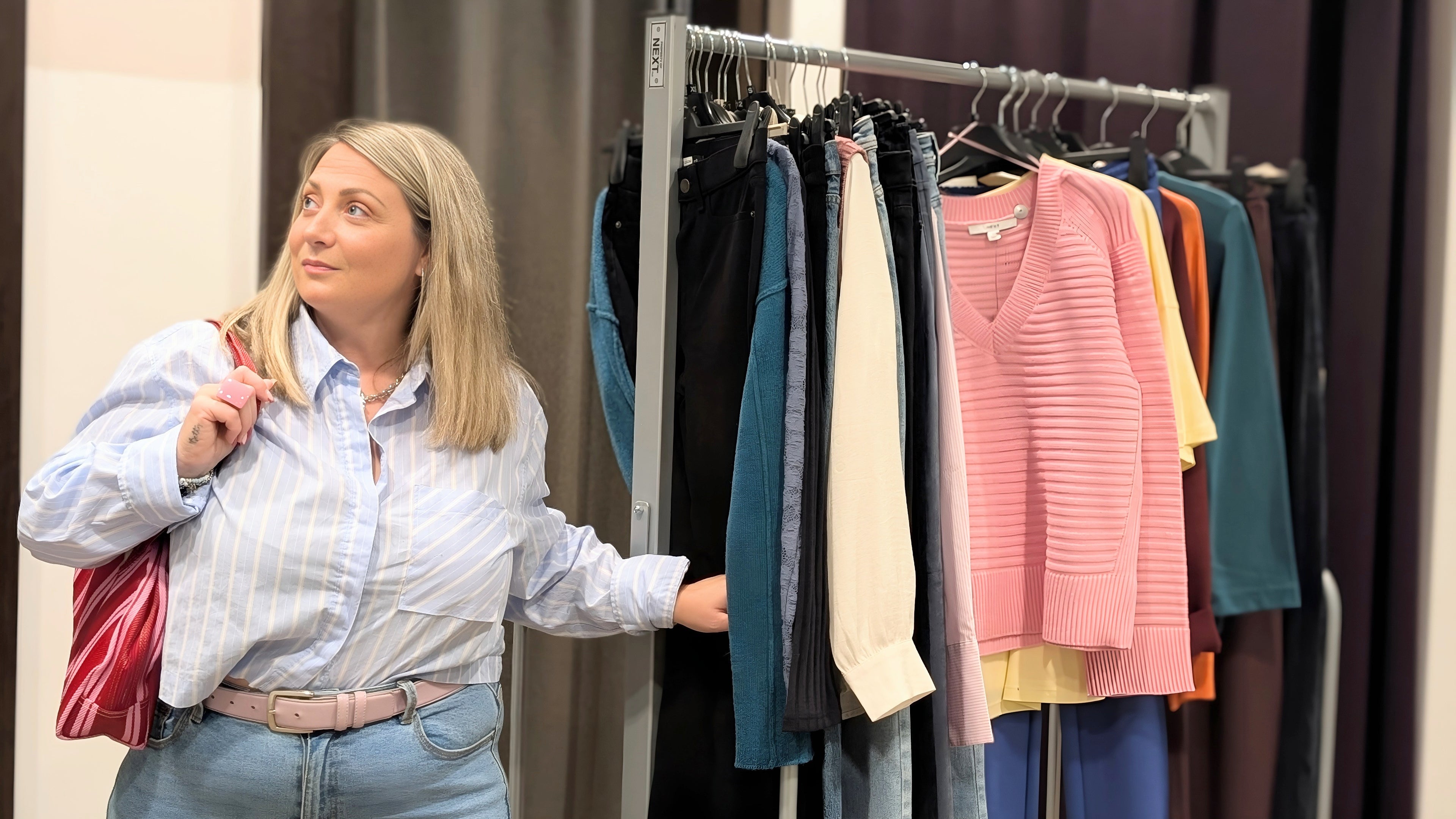 Hazel guiding a client through outfit choices during a personal shopping consultation in a boutique.